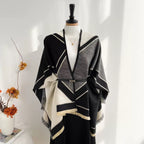 The Noir Geometry Cashmere Cape draped over shoulders in cape style showing geometric noir print and full-coverage silhouette
