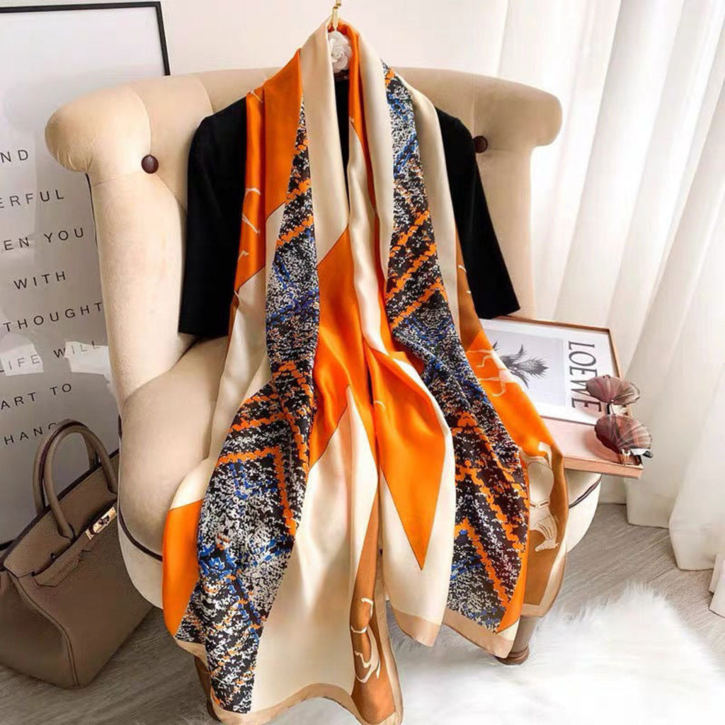 Orange beige equestrian print silk scarf draped on chair - horse motif luxury scarf with chain border