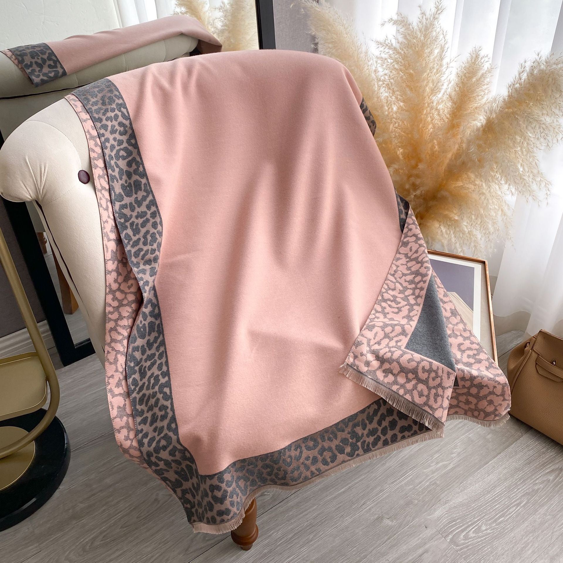 Rosewood Leopard Trim Wrap draped over a chair showing reversible grey side with blush leopard border