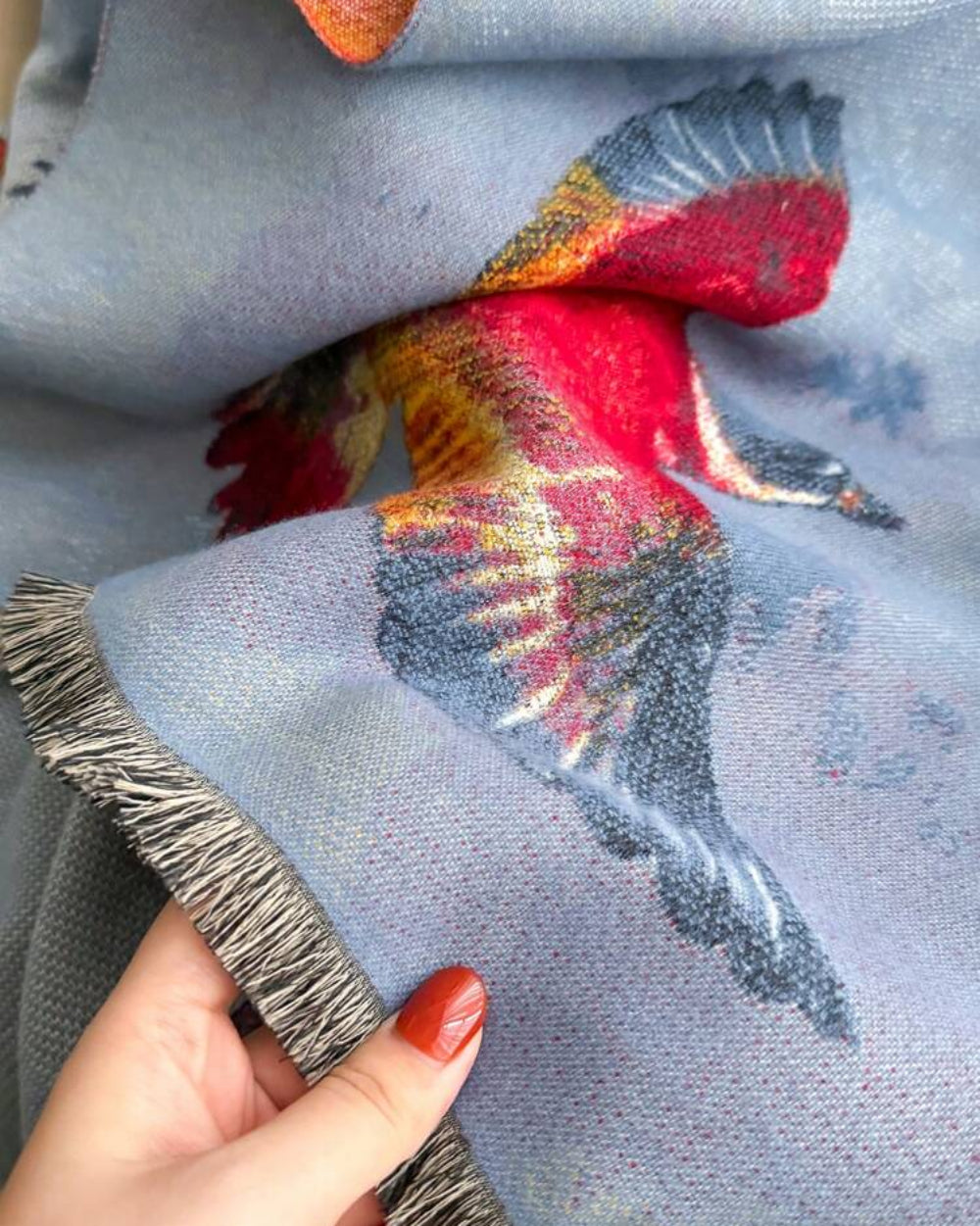 Close-up of The Skybound Aviary Reversible Wrap showing soft faux cashmere fabric texture with detailed bird and botanical aviary motif print
