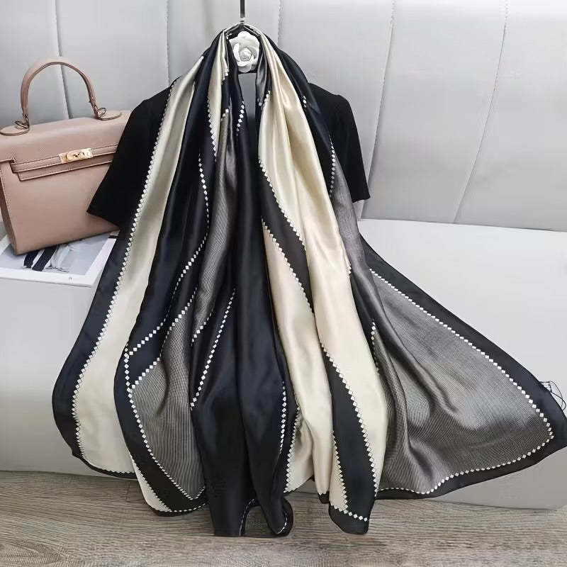 The Duchess Diamond Silk Stole in black and ivory geometric print, premium satin silk scarf displayed in an elegant luxury setting.