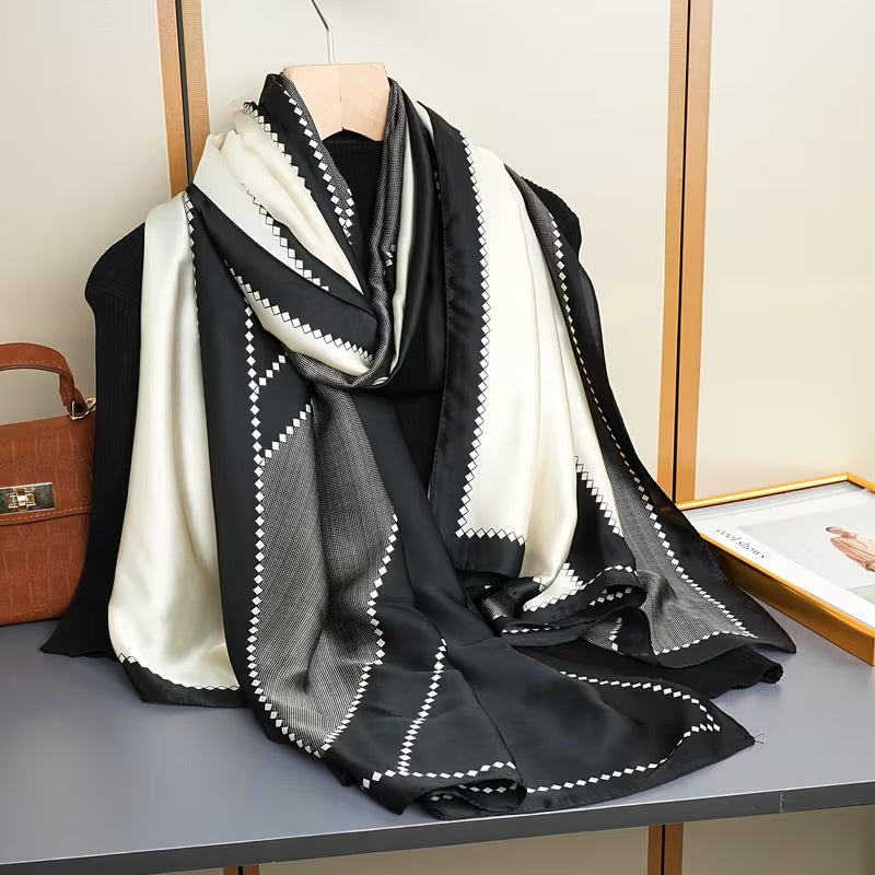     The Duchess Diamond Silk Stole featuring an elegant black and ivory diamond pattern draped beautifully to showcase its luxurious silk finish.