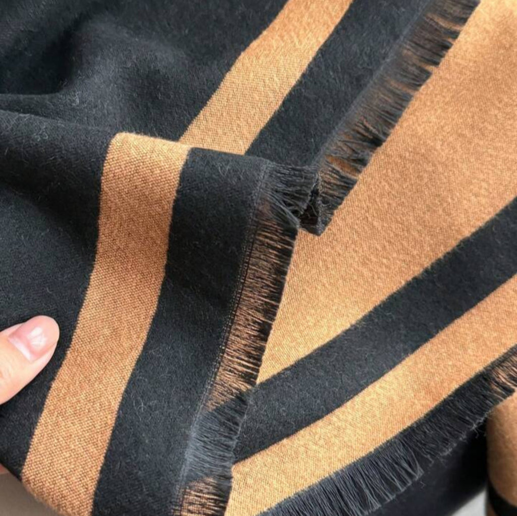     Detailed view of the fringed edges and woven texture of The Signature Reversible Black & Tan Border Wrap in jacquard faux cashmere, measuring 182 x 65 cm.