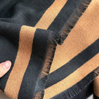     Detailed view of the fringed edges and woven texture of The Signature Reversible Black & Tan Border Wrap in jacquard faux cashmere, measuring 182 x 65 cm.