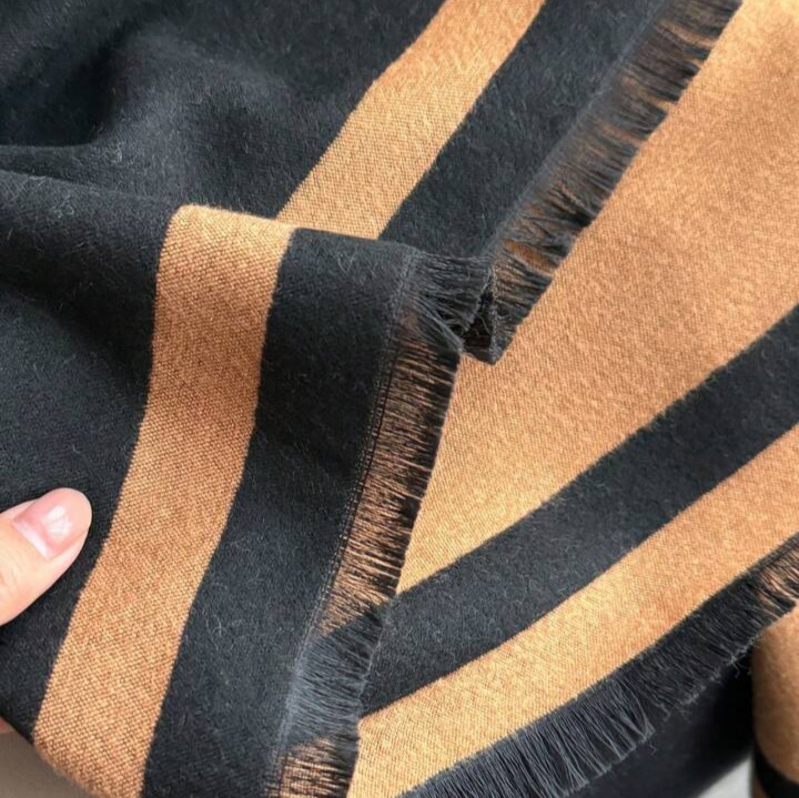    Detailed view of the fringed edges and woven texture of The Signature Reversible Black & Tan Border Wrap in jacquard faux cashmere, measuring 182 x 65 cm.