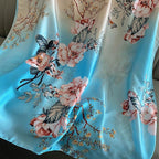 Westery Blooming Garden luxury silk scarf styled elegantly in a flat lay next to a lifestyle magazine and sunglasses, highlighting its sophisticated multi-toned layout and fluid, elegant drape.
