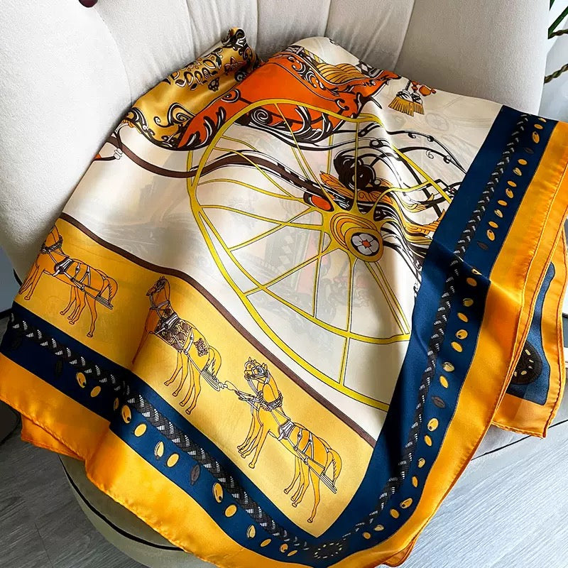 The Golden Carriage Equestrian luxury silk stole by Westery neatly arranged to display the repeating golden horse motifs along the border and a large decorative carriage wheel print.
