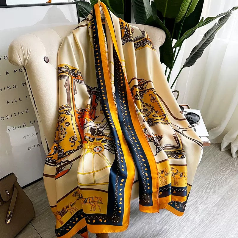 Golden Carriage Equestrian luxury silk stole by Westery draped vertically over an armchair, showcasing the rich mustard yellow, navy blue, and cream color palette with detailed royal carriage motifs.
