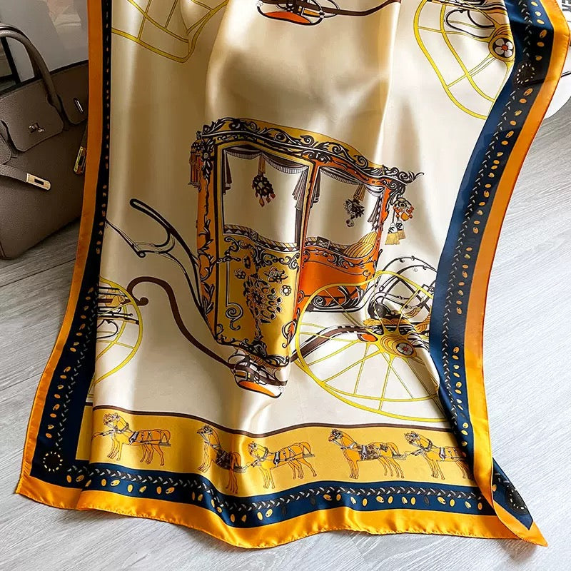 Detailed view of the Westery Golden Carriage Equestrian silk scarf spread out to reveal the intricate illustration of a royal horse-drawn carriage and an ornate golden border.
