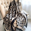 Grand Maze Graphic luxury silk stole by Westery draped elegantly over an armchair, showcasing its bold black geometric greek-key style pattern on a premium beige silk fabric.
