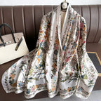 Westery Imperial Garden Bird & Bloom luxury silk scarf styled as a layered neck wrap on a hanger over a black blazer, emphasizing the rich contrast of multi-colored blossoms against a clean background.
