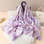 Lavender Magnolia luxury silk scarf by Westery cascading elegantly from a designer handbag onto a white faux fur rug, showcasing its premium satin luster and fluid, graceful drape.
