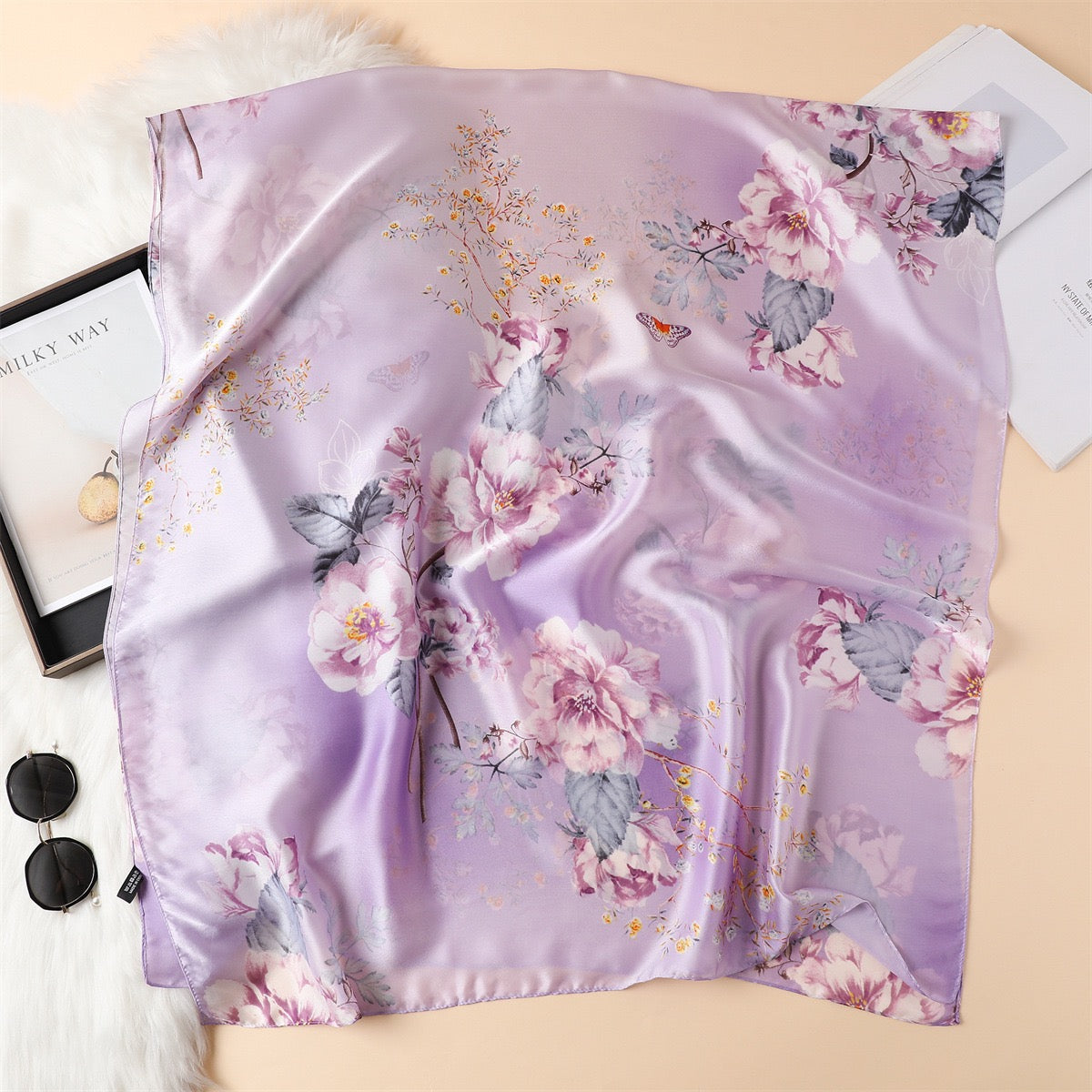 Full flat-lay view of the Westery Lavender Magnolia premium silk scarf, displaying the intricate violet and blush floral motifs, detailed greyish-green foliage, and delicate gold wildflower branches across a soft purple ombré background.
