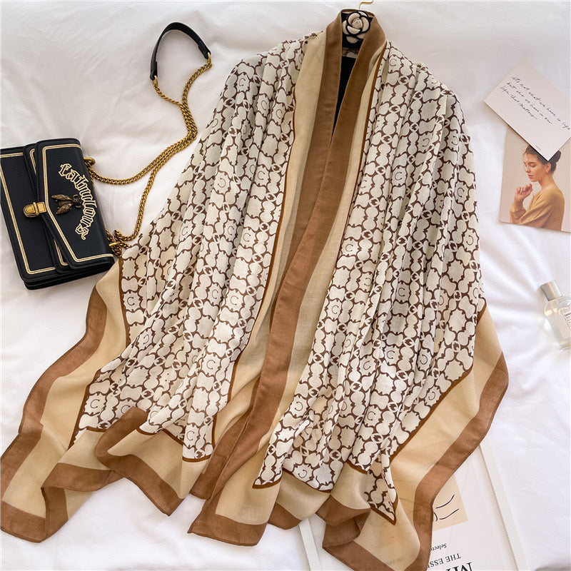 Moroccan Lattice Luxe premium viscose cotton stole by Westery displayed on a white surface next to a luxury black chain bag, showcasing its repeating tan geometric monogram pattern and elegant camel-toned borders.
