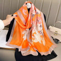 ⁠Sunkissed Lily luxury silk stole by Westery, featuring a vibrant orange fabric with an elegant white lily floral pattern and a neutral border.
