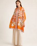 Sunkissed Lily luxury silk stole by Westery, featuring a vibrant orange fabric with an elegant white lily floral pattern and a neutral border worn by a model 