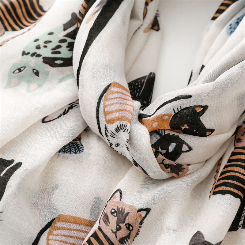 An angled overhead view of the Westery Whisker Tales premium novelty scarf layout, demonstrating the continuous repeating motif of playful cat illustrations and soft muted accent colors.
