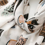 An angled overhead view of the Westery Whisker Tales premium novelty scarf layout, demonstrating the continuous repeating motif of playful cat illustrations and soft muted accent colors.
