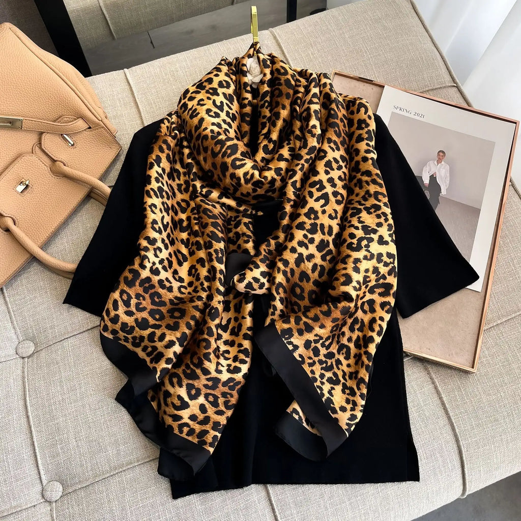 Wild Luxe Leopard luxury silk stole by Westery styled in an elegant drape on a hanger, showcasing its bold animal print pattern, rich golden-brown tones, and a solid black border.
