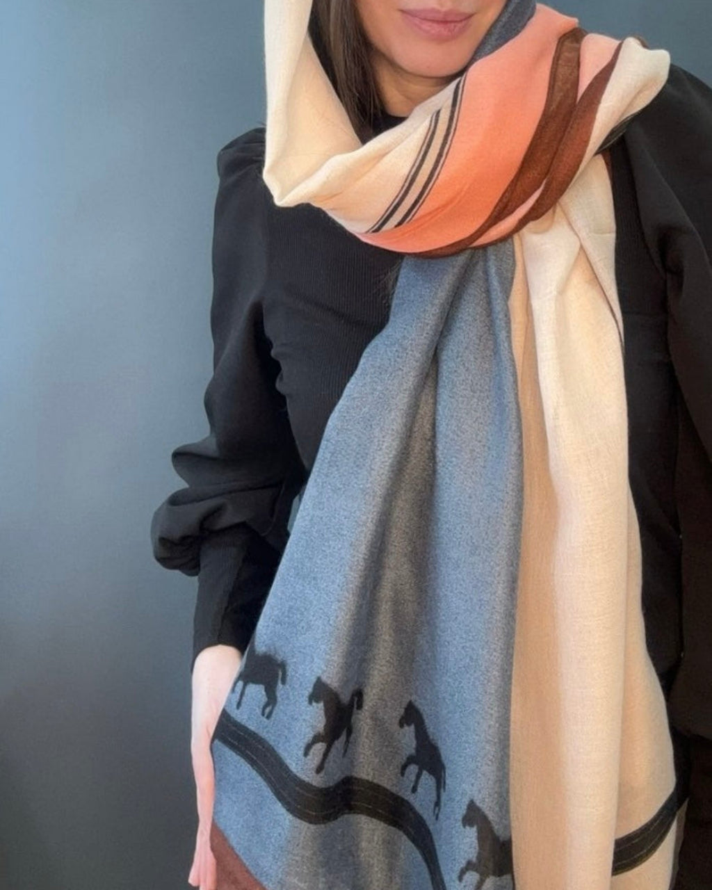 Westery Wild Spirit Equestrian premium scarf styled to highlight the slate blue colour block panel featuring running horses, draped elegantly with cream and peach tones.
