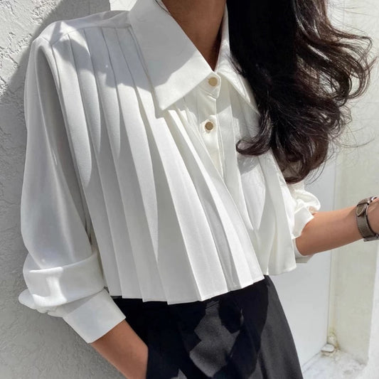 Close-up of white pleated cape collar shirt showing vertical pleats and pointed collar detail