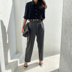 Woman wearing black  pleated cape collar blouse with black pants - elegant professional styling