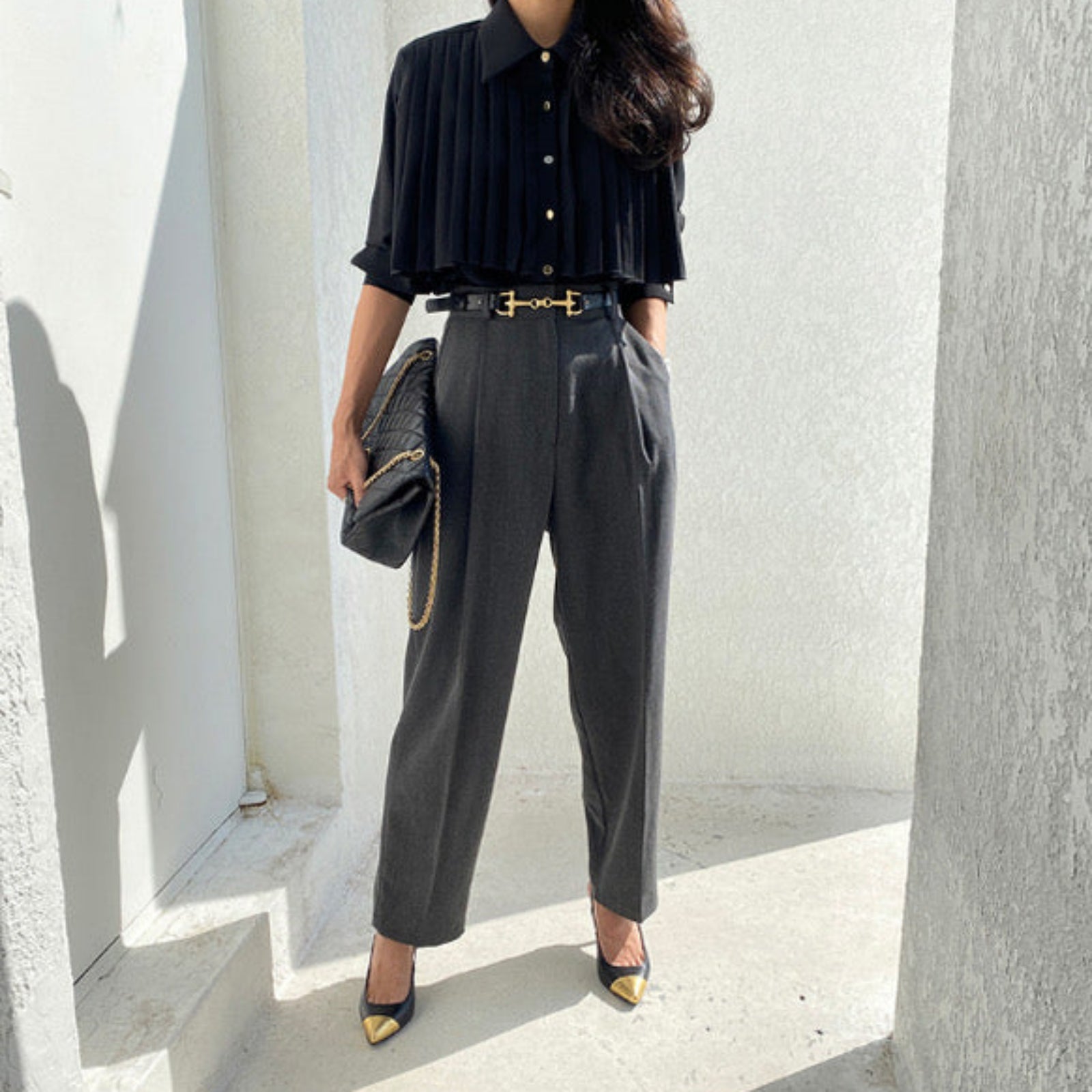 Woman wearing black  pleated cape collar blouse with black pants - elegant professional styling