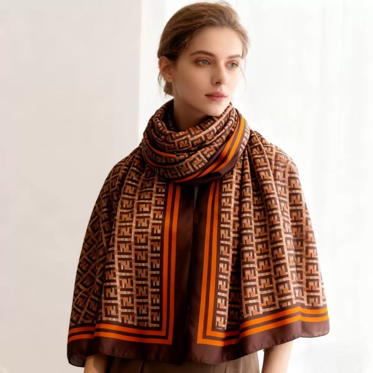Woman wearing brown beige orange monogram print scarf wrapped - luxury designer scarf styling close-up