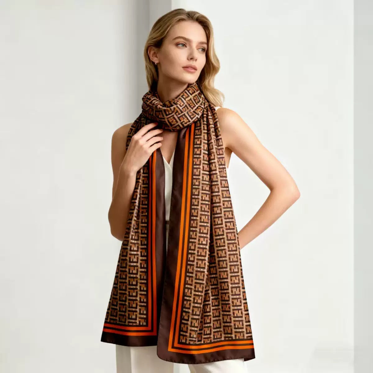 Woman wearing designer geometric monogram scarf with white top - elegant draping style brown beige orange