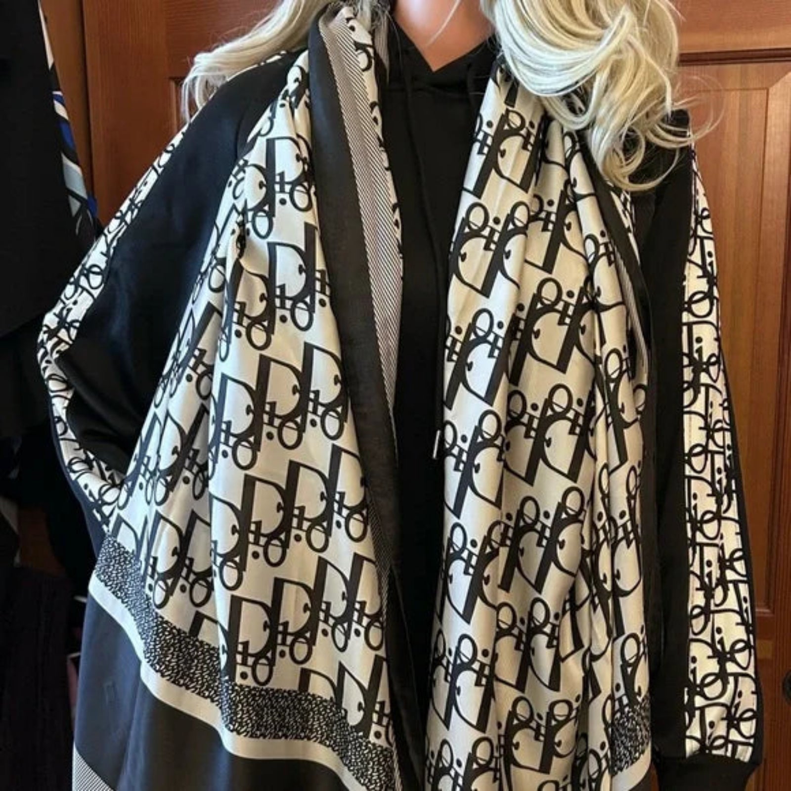 Woman wearing beige black designer logo print stole around neck with black outfit - luxury styling